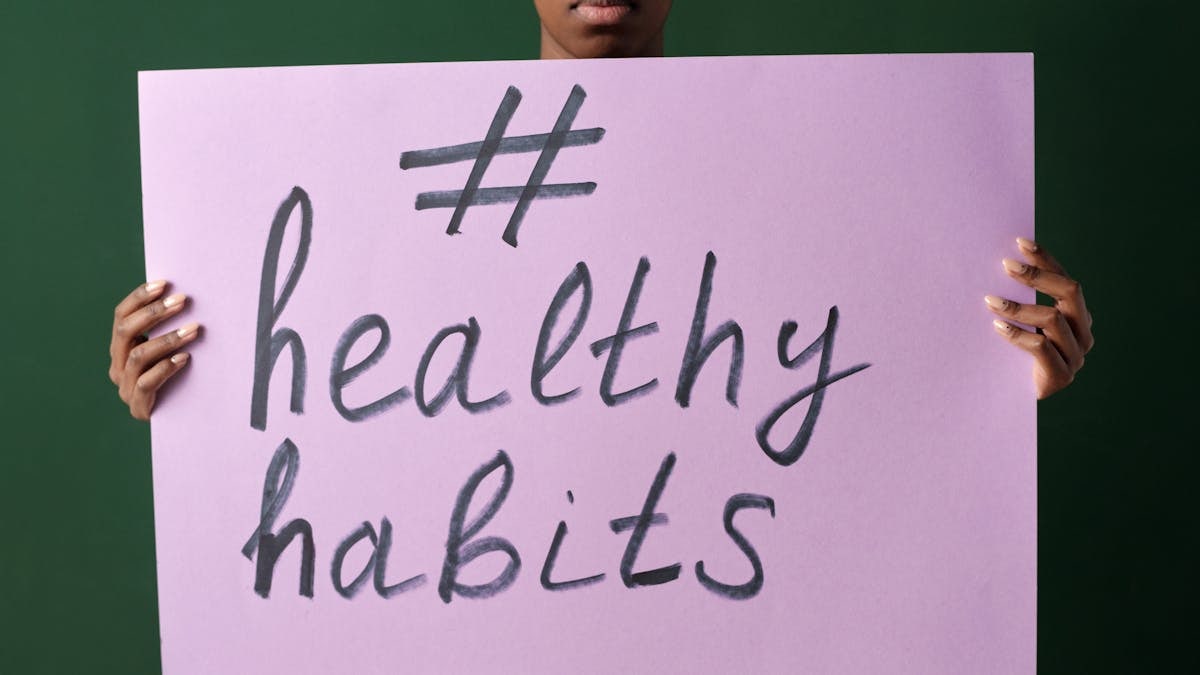 Person holding a "#healthyhabits" sign, emphasizing wellness.